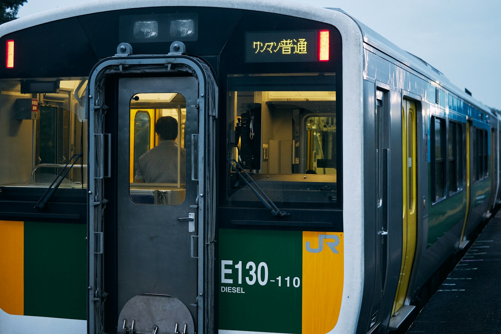 緑と黄色の帯をまとった通勤電車